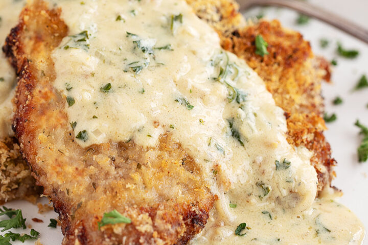 Oven-baked panko breaded pork chops on plate with mustard sauce.