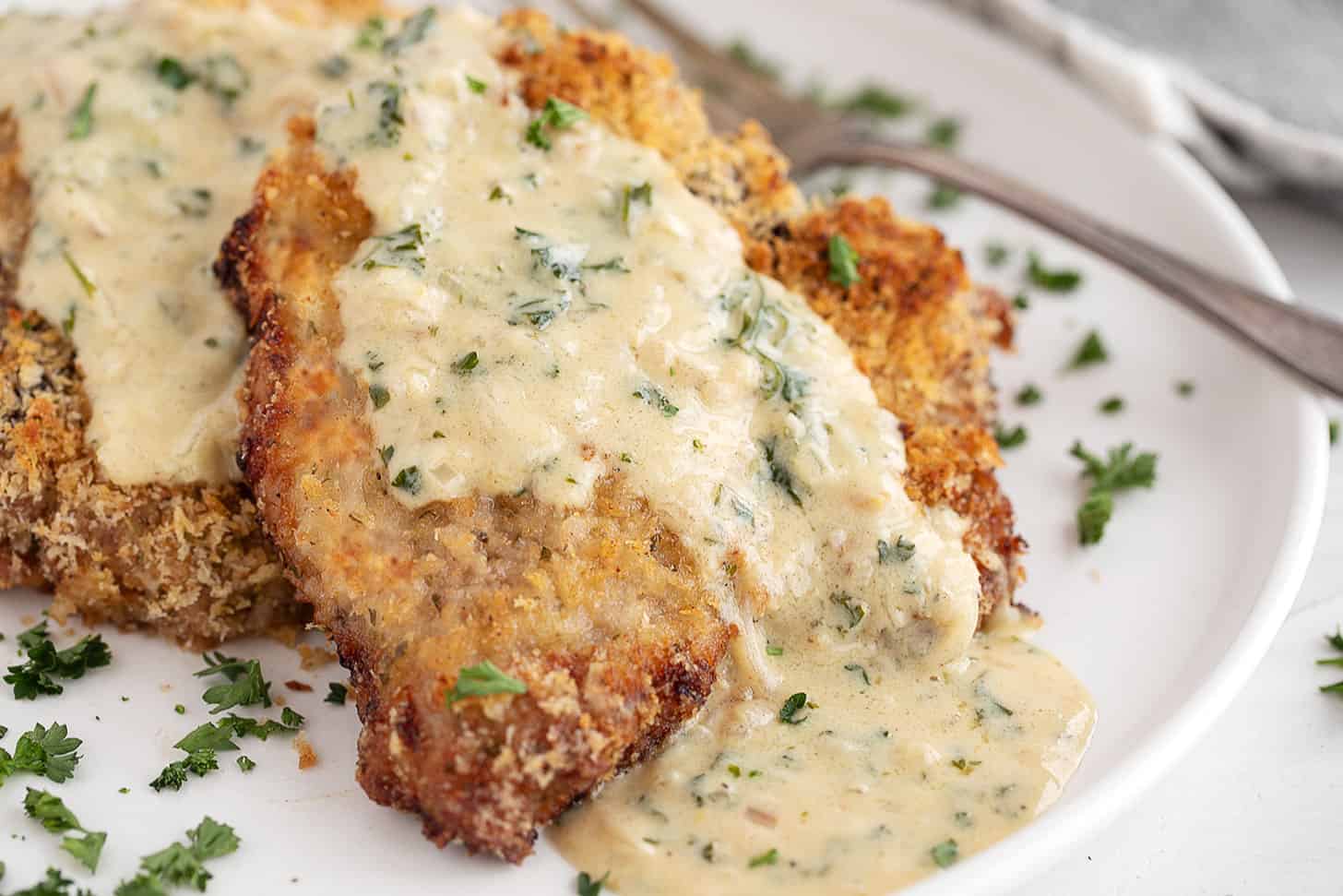 Oven-baked panko breaded pork chops on plate with mustard sauce.