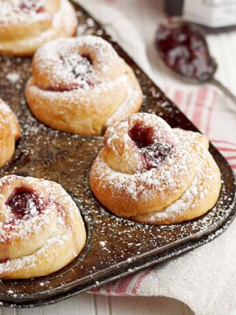 rose shaped buns in muffin tin with raspberry jam