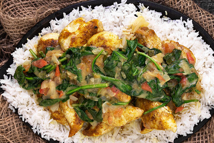 Brazilian chicken curry with spinach in skillet with rice