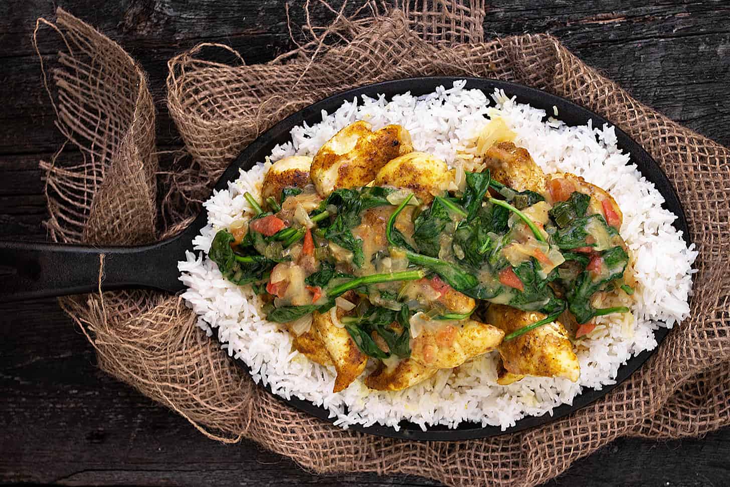 Brazilian chicken curry with spinach in skillet with rice