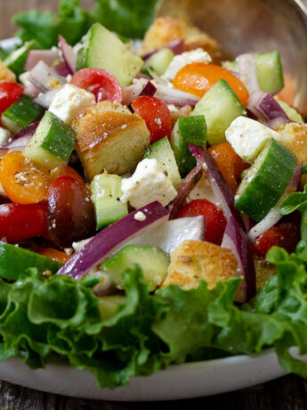 Greek panzanella salad in bowl with lettuce