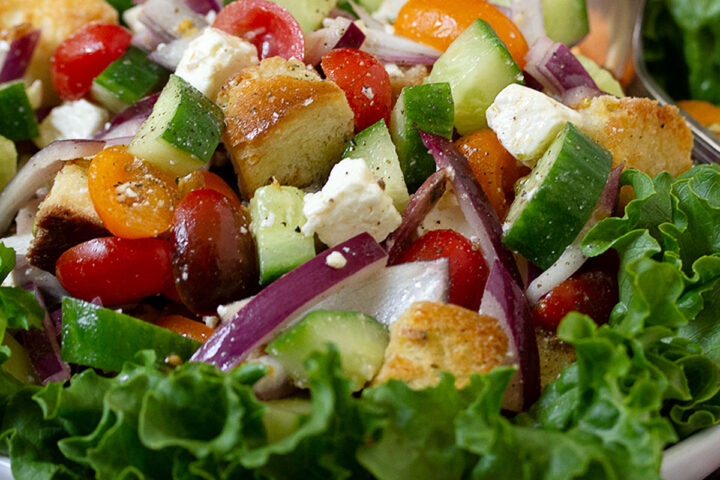 Greek panzanella salad in bowl with lettuce