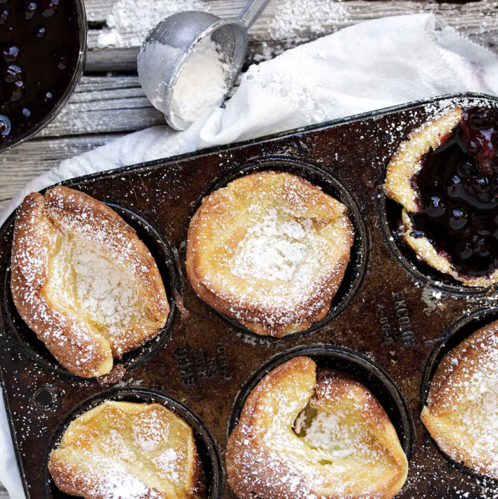 mini dutch babies in muffin tin with blueberry sauce
