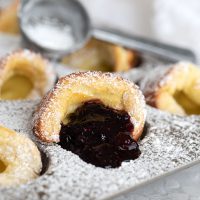 mini dutch babies in muffin tin with blueberry sauce