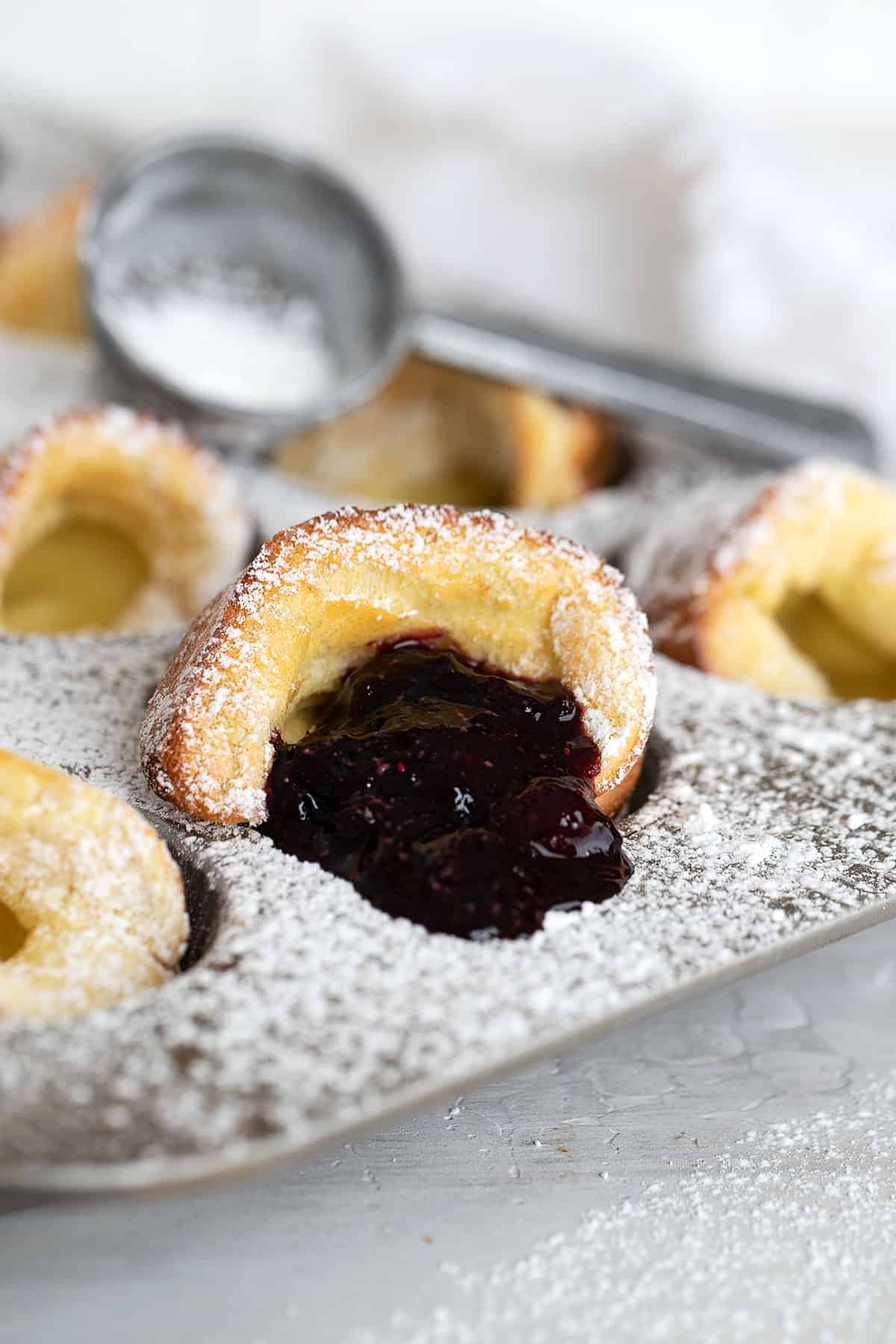 mini dutch babies in muffin tin with blueberry sauce