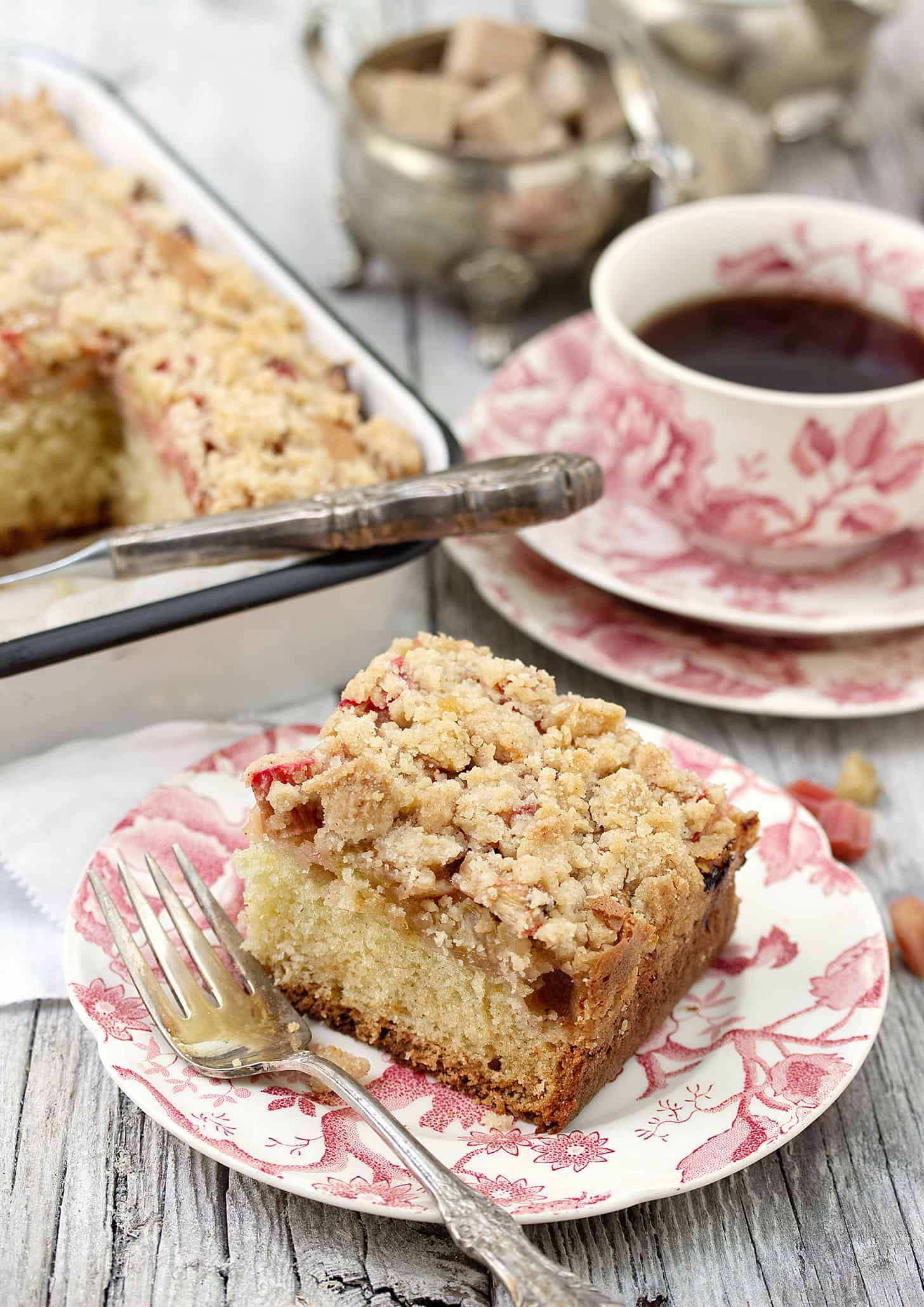 rhubarb coffee cake sliced on plate with cup of coffee