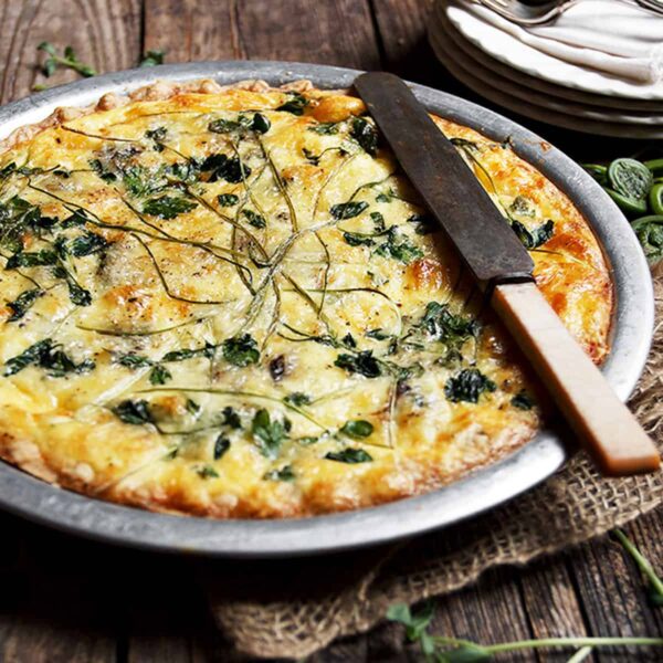 fiddlehead quiche in pie plate with knife