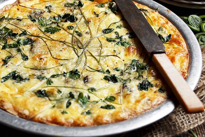 fiddlehead quiche in pie plate with knife