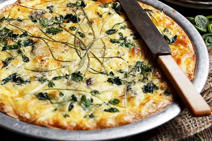 fiddlehead quiche in pie plate with knife