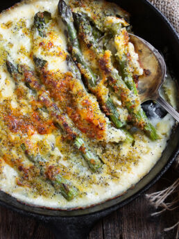 baked asparagus with cheese sauce in cast iron skillet