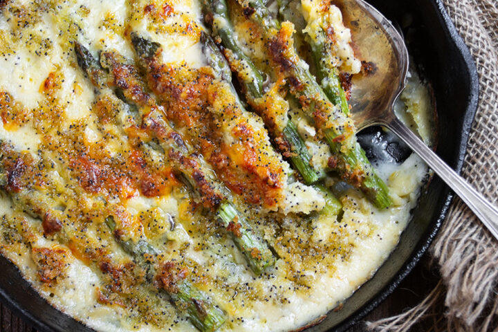 baked asparagus with cheese sauce in cast iron skillet