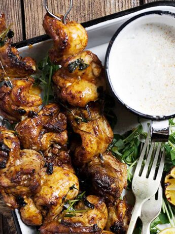 Portuguese chicken skewers on platter with lemons