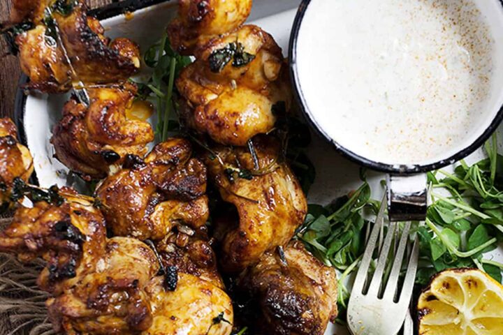 Portuguese chicken skewers on platter with lemons