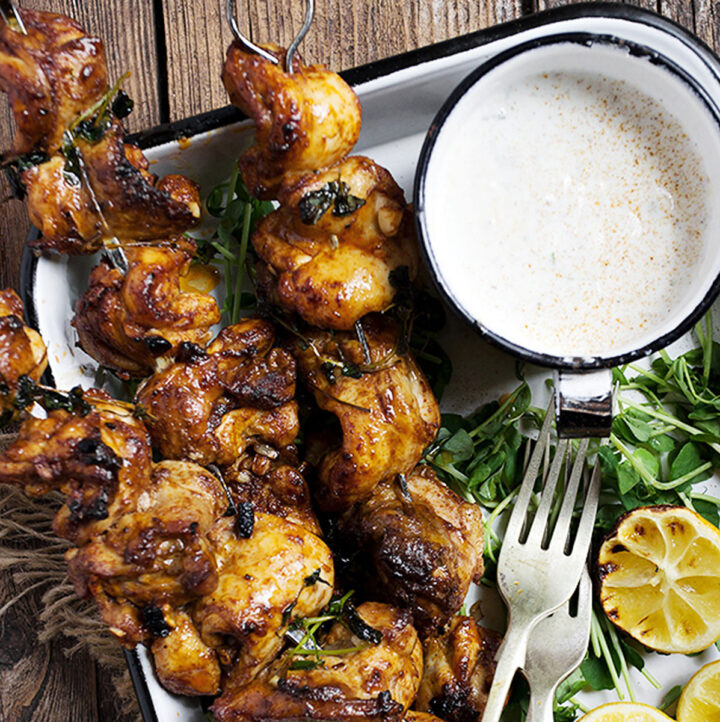 Portuguese chicken skewers on platter with lemons