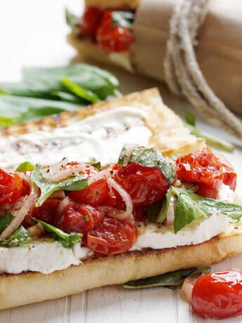 blistered tomato caprese sandwiches on white background