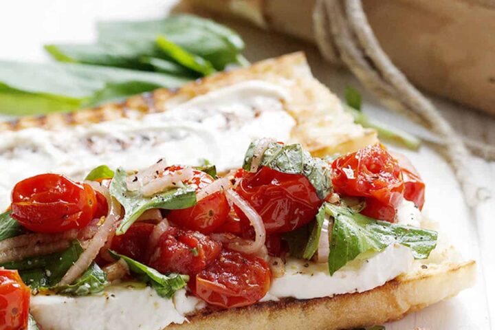 blistered tomato caprese sandwiches on white background