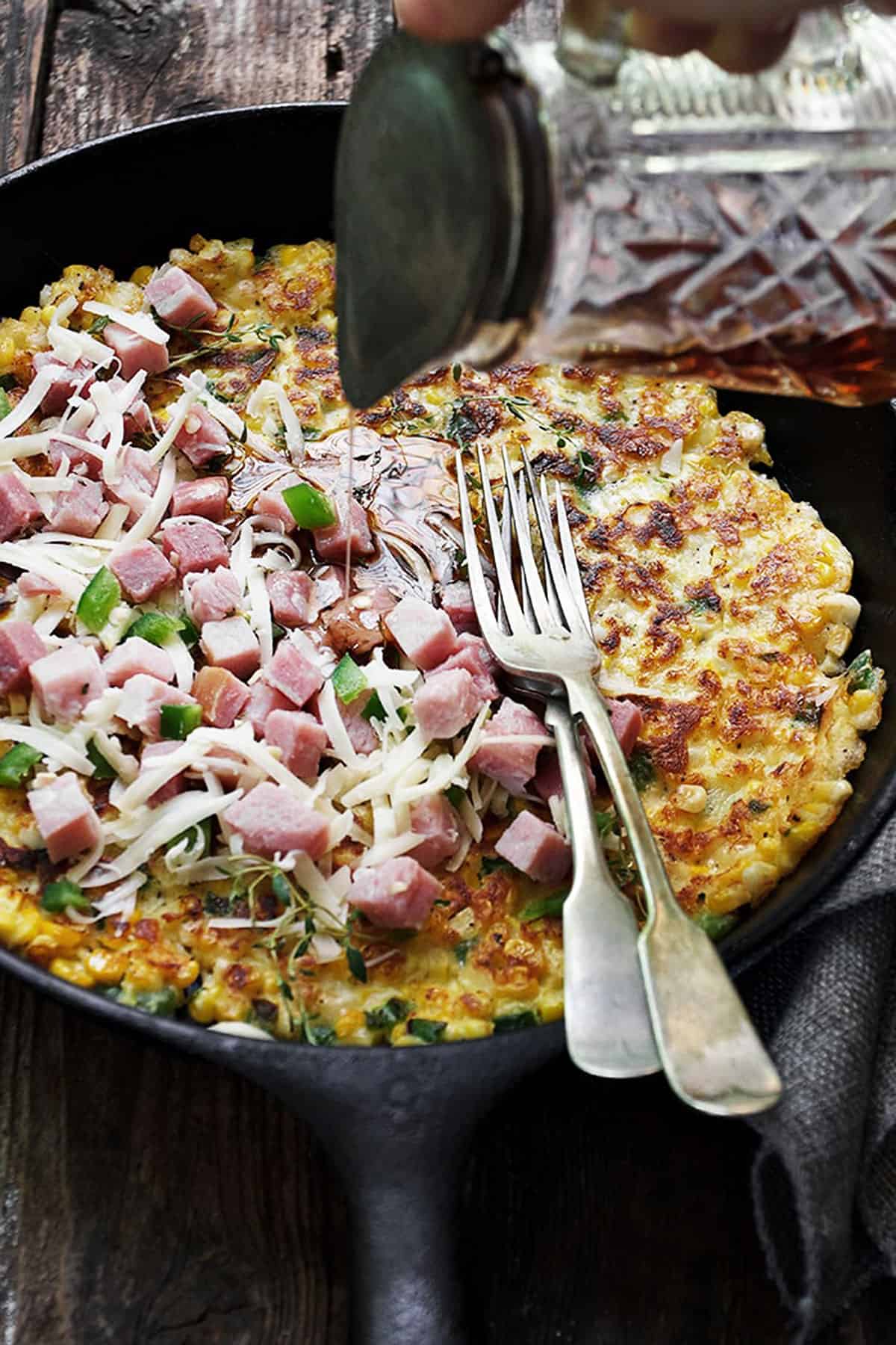 savoury corn pancake in skillet with ham and cheese