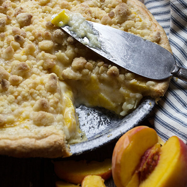 peaches and cream pie in pie pan with slice out