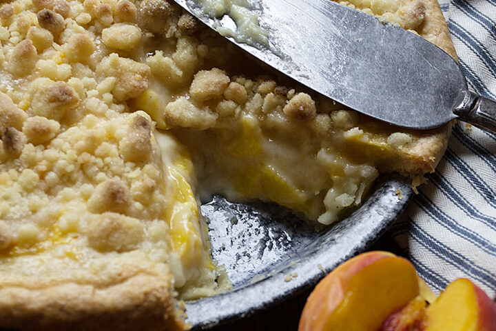 peaches and cream pie in pie pan with slice out