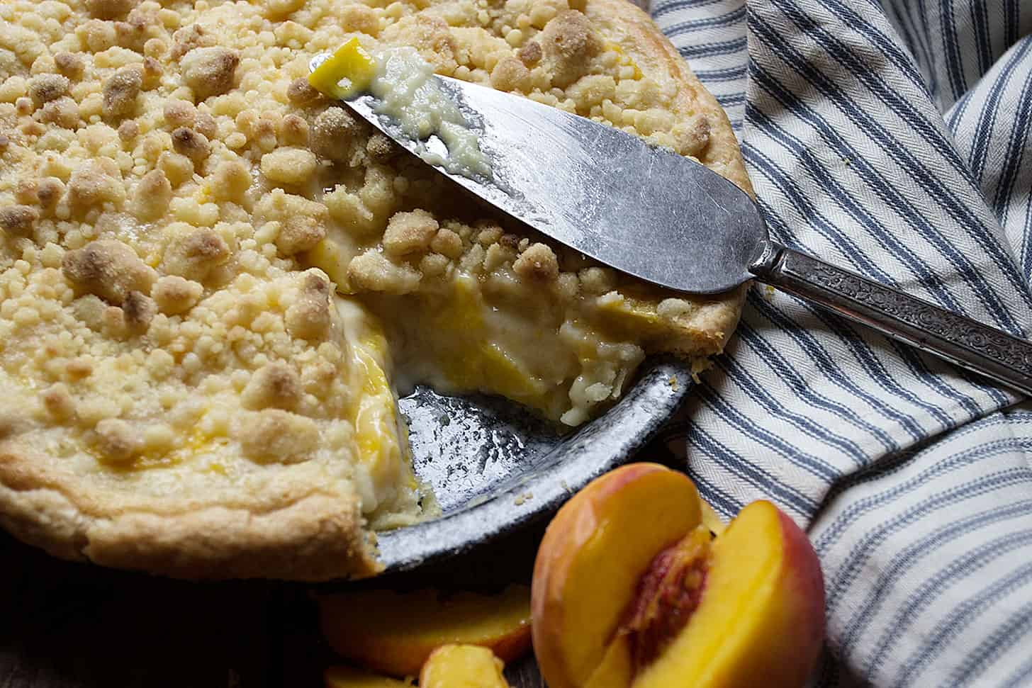 peaches and cream pie in pie pan with slice out