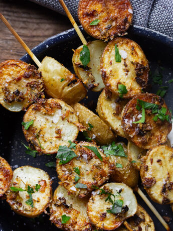 Herb roasted potato skewers in a skillet with sour cream.