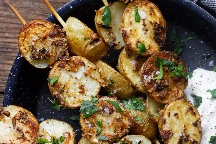 Herb roasted potato skewers in a skillet with sour cream.