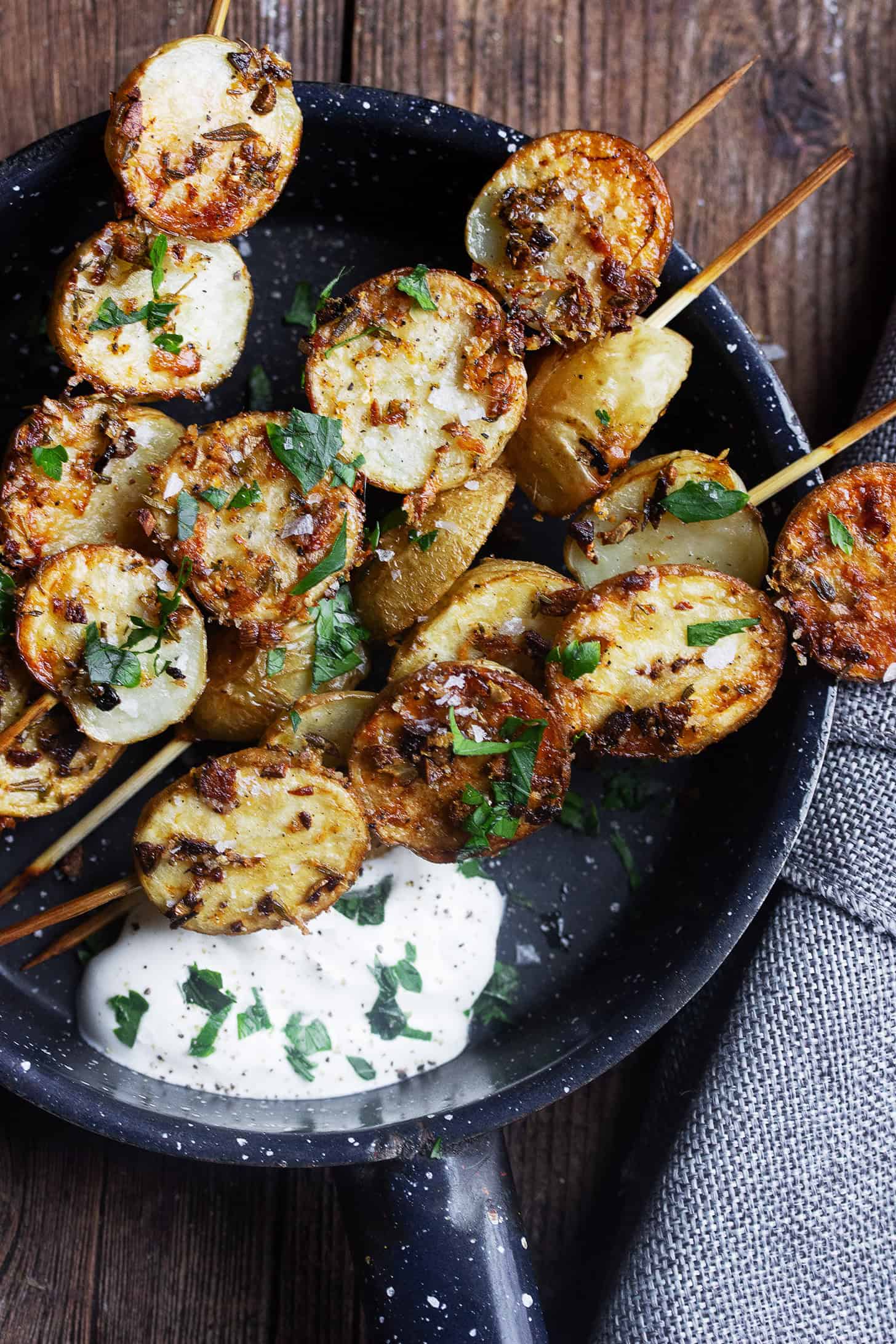 Herb roasted potato skewers in a skillet with sour cream.