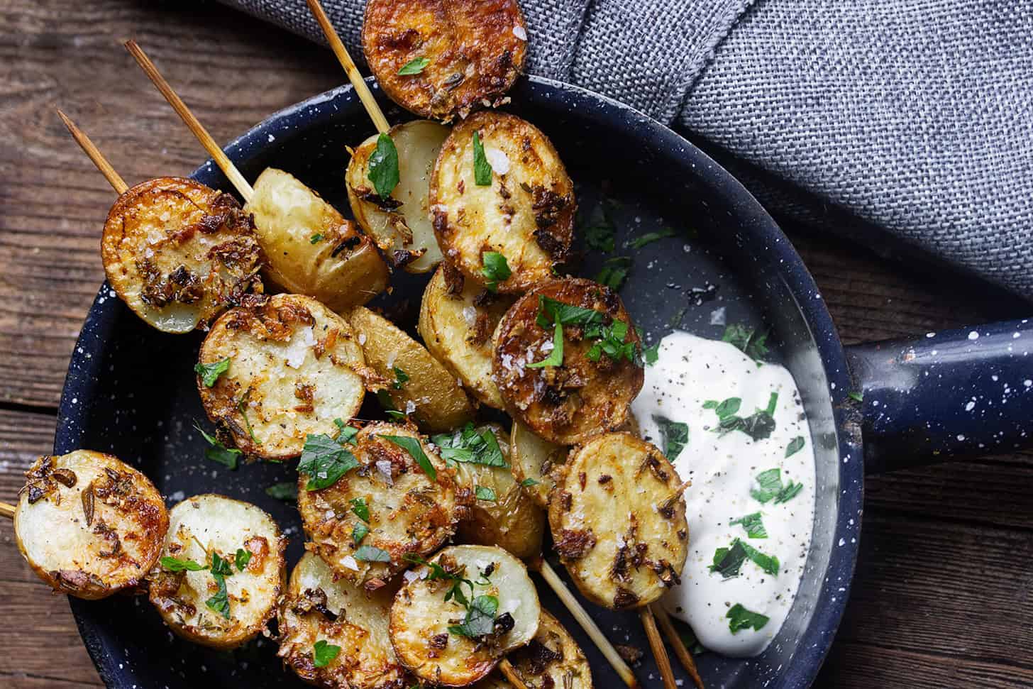 Herb roasted potato skewers in a skillet with sour cream.