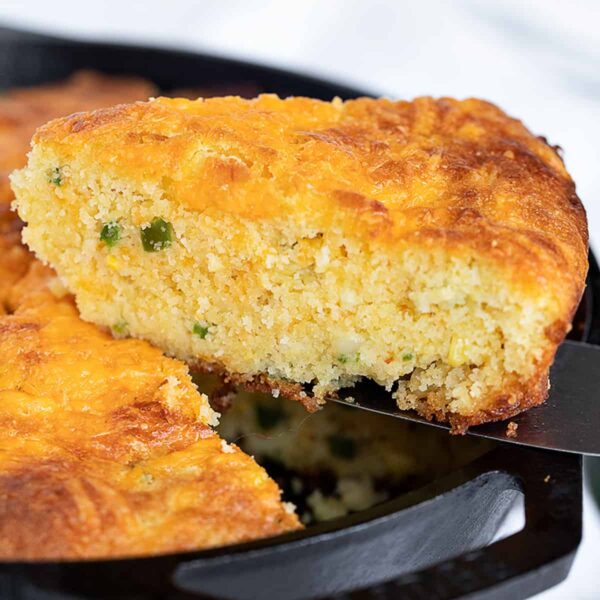 jalapeno cheddar cornbread in cast iron skillet with slice out