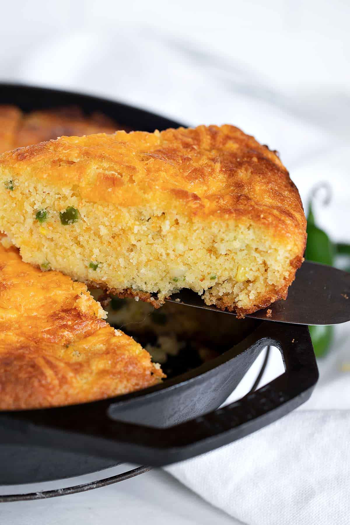 jalapeno cheddar cornbread in cast iron skillet with slice out