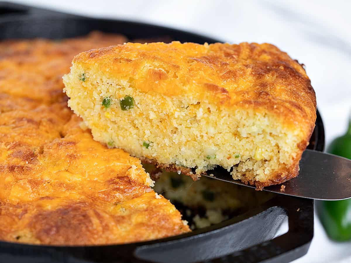 jalapeño cheddar cornbread in cast iron skillet with slice out