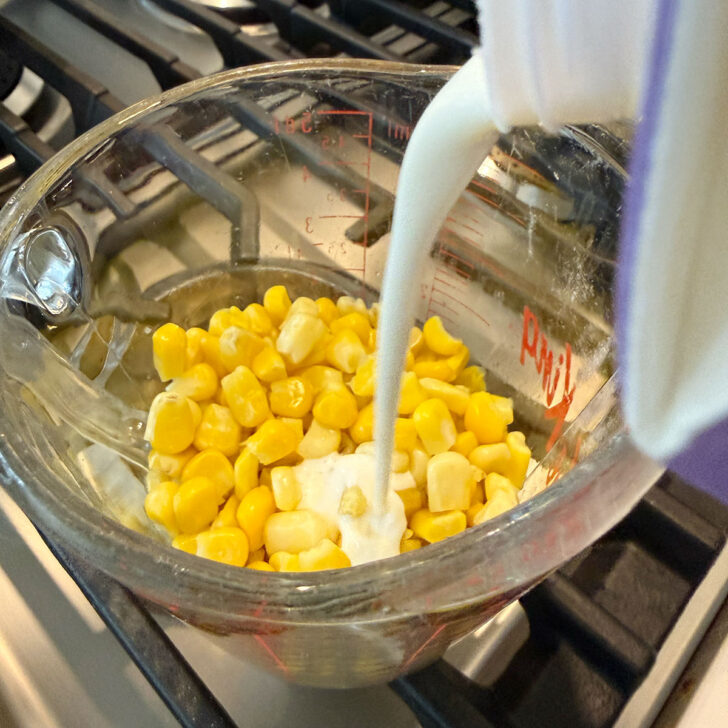 Adding cream to a measuring cup with corn kernels.