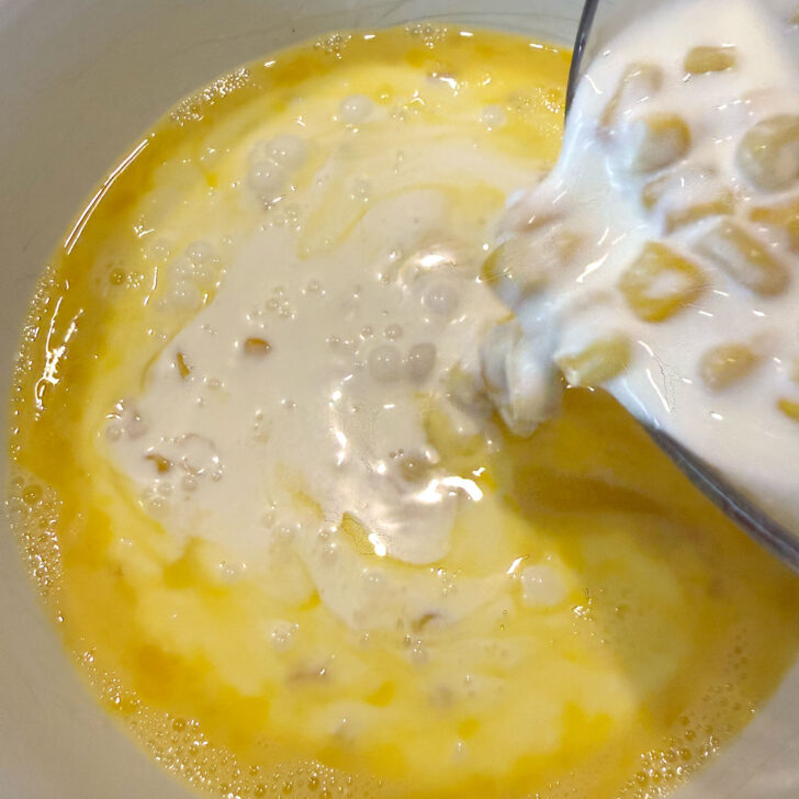 Adding the corn and cream mixture to the beaten eggs.