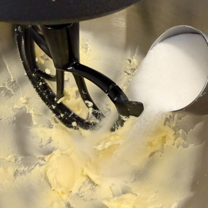 Adding sugar to the butter in a stand mixer.