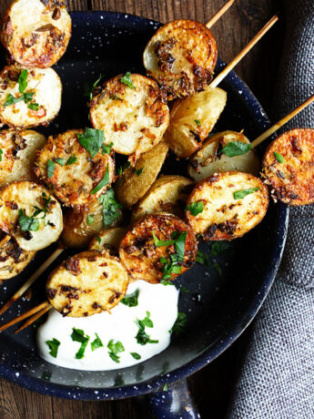 herb and garlic potato skewers in skillet with sour cream
