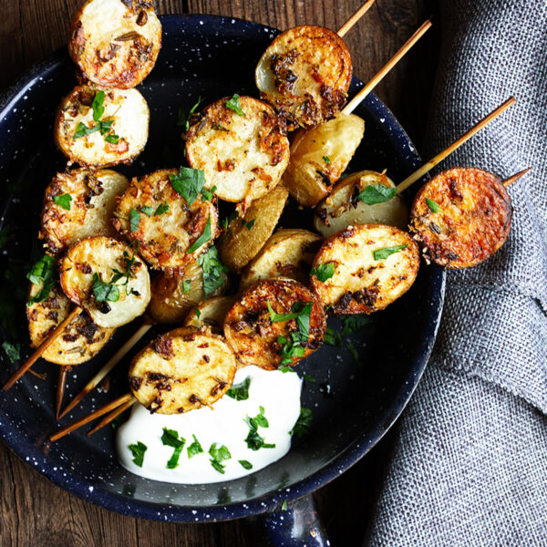 herb and garlic potato skewers in skillet with sour cream