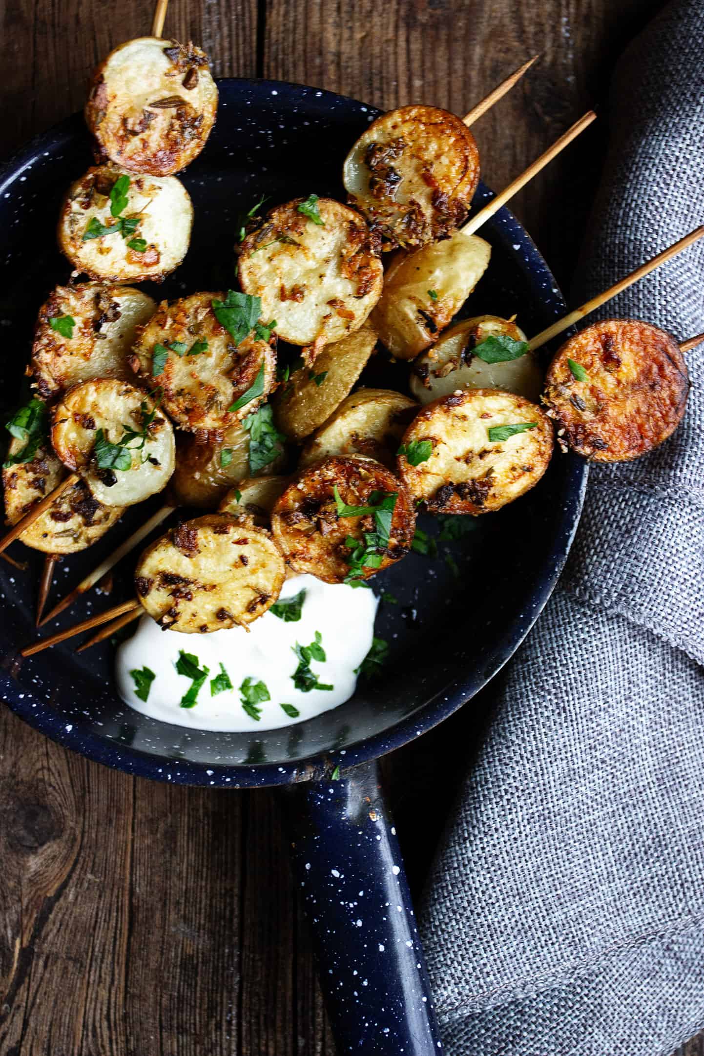 herb and garlic potato skewers in skillet with sour cream