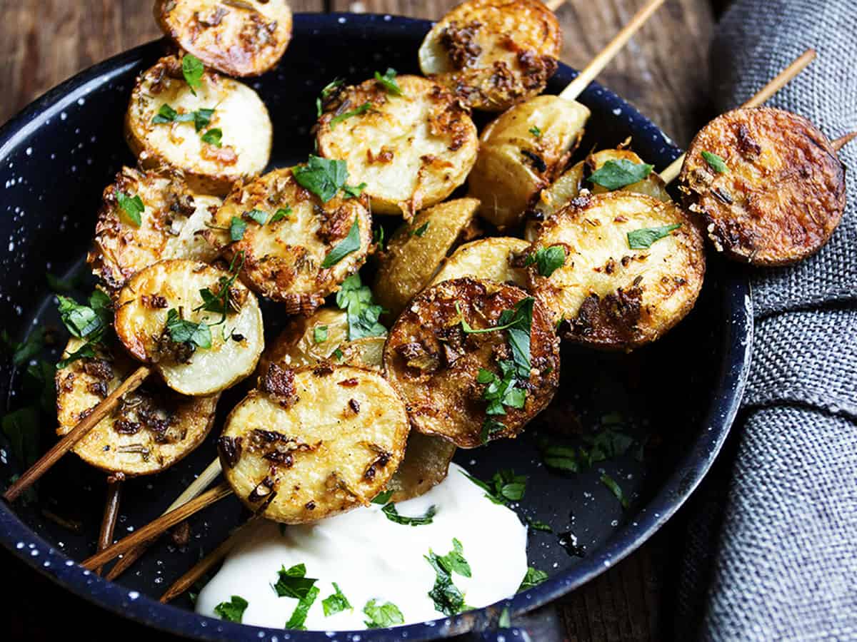 herb and garlic potato skewers in small skillet
