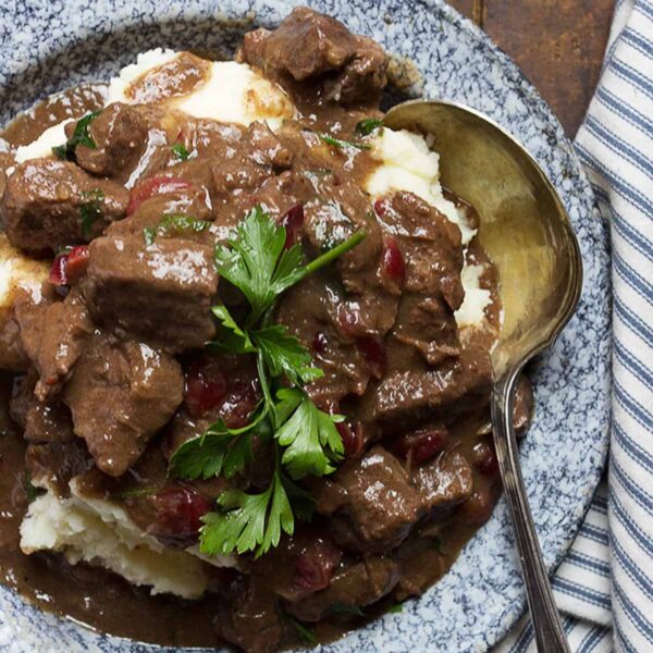 braised beef with cranberries on plate with mashed potatoes