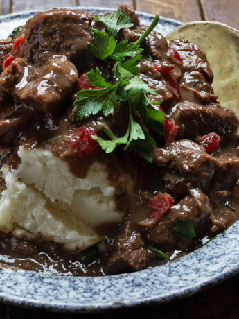 cranberry beef stew on plate with mashed potatoes