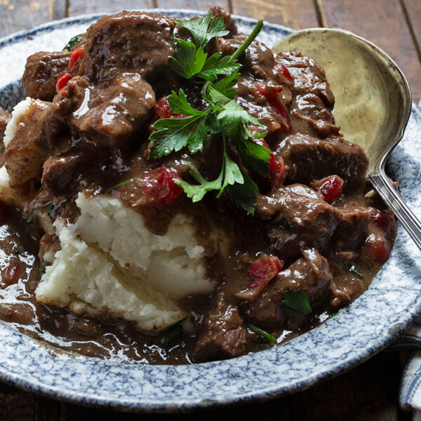 cranberry beef stew on plate with mashed potatoes
