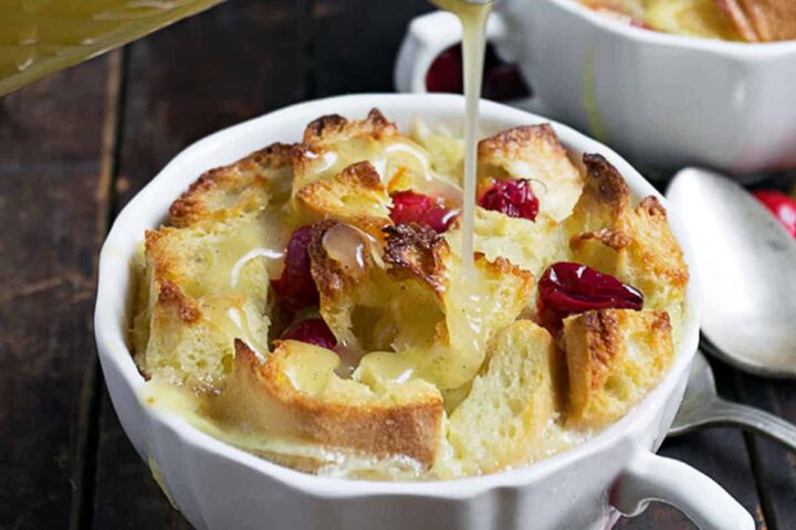 cranberry orange bread pudding with warm butter sauce being poured