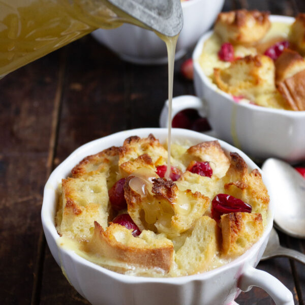 cranberry orange bread pudding with butter sauce being poured