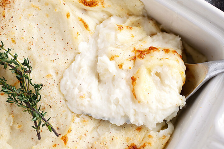 Make-ahead mashed potatoes in a casserole dish being spooned out.