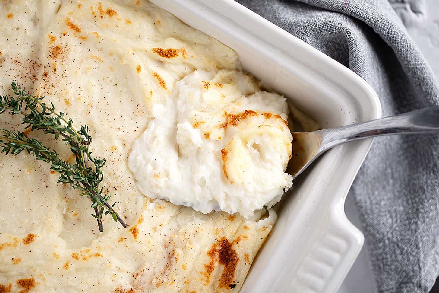 Make-ahead mashed potatoes in a casserole dish being spooned out.