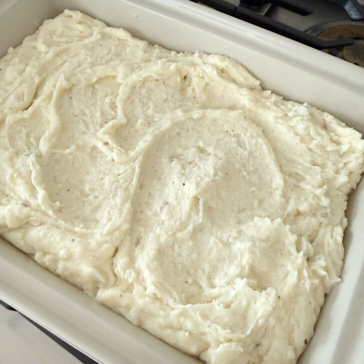 Make-ahead mashed potatoes spooned into a casserole dish.