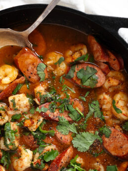 Spicy chorizo and shrimp in a cast iron skillet with spoon.