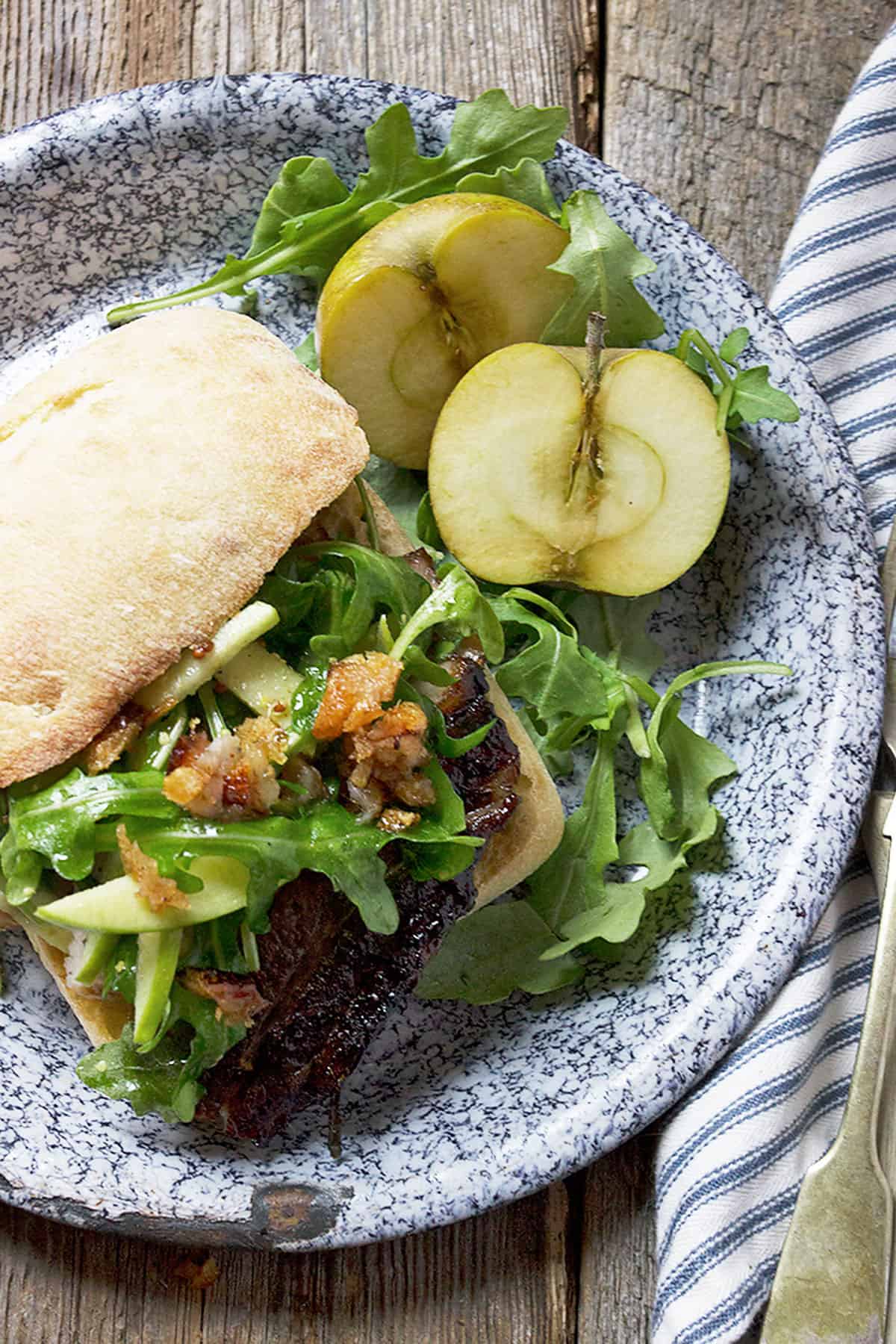 pork belly sandwich on plate with apple