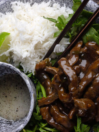beef and watercress stir fry on platter with rice and dipping sauce